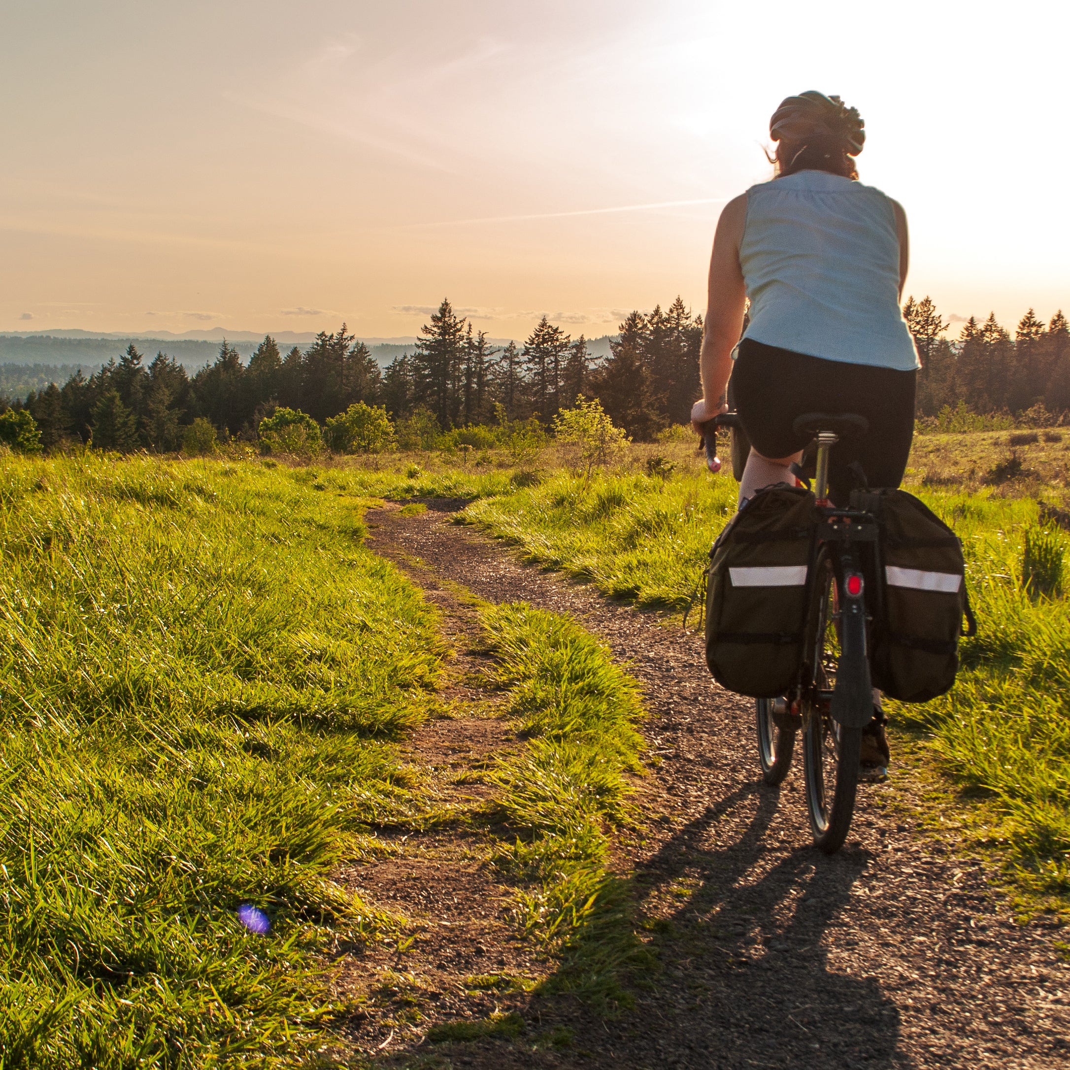 woman biking along a dirt path at sunset