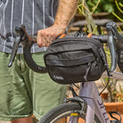 Person holding a black bike bag on a bicycle with a blurred background all-groups