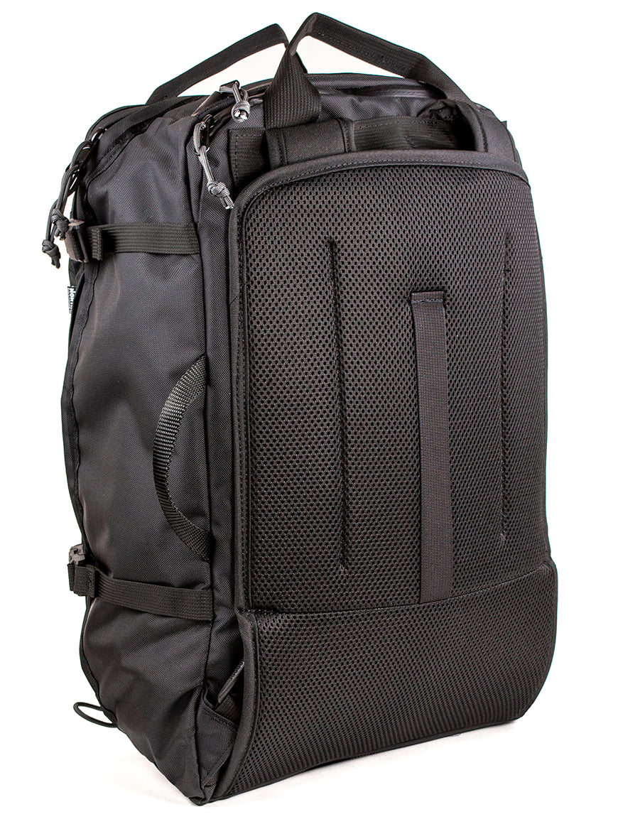 Back view of a black travel backpack showing stow-able backpack straps and carry handles on a white background. 